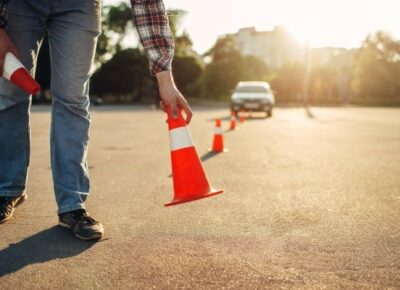 A person placing cones in front of a car.