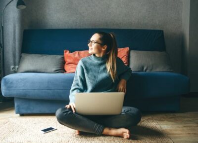 A woman looking into the air while holding a laptop.