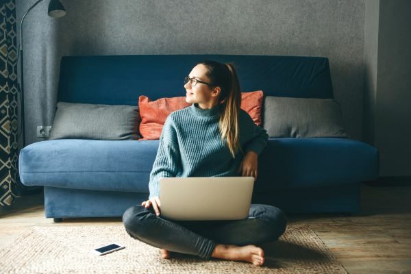 A woman looking into the air while holding a laptop.