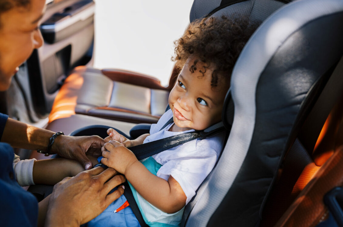 A child sitting in their car seat and smiling.