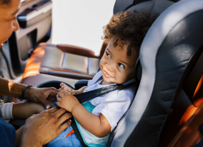 A child sitting in their car seat and smiling.