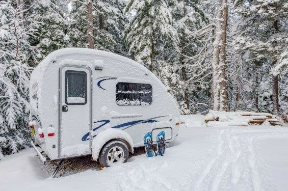 A travel trailer parked in the snow.