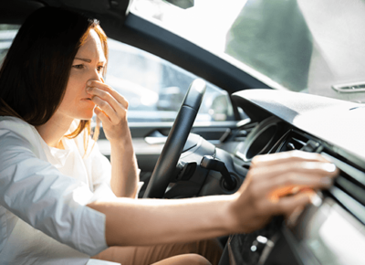 Woman in car reacting to a bad smell.