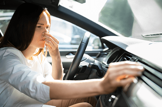 Woman in car reacting to a bad smell.