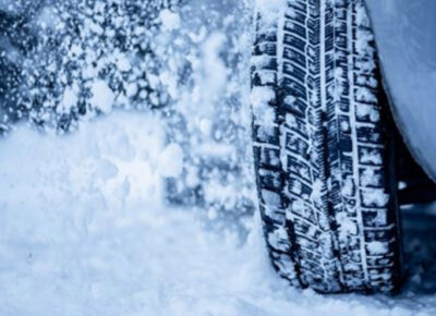 A tire covered in snow driving through a snowstorm.