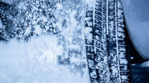 A tire covered in snow driving through a snowstorm.