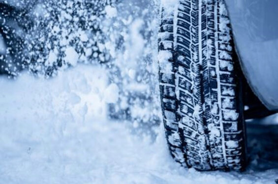 A tire covered in snow driving through a snowstorm.