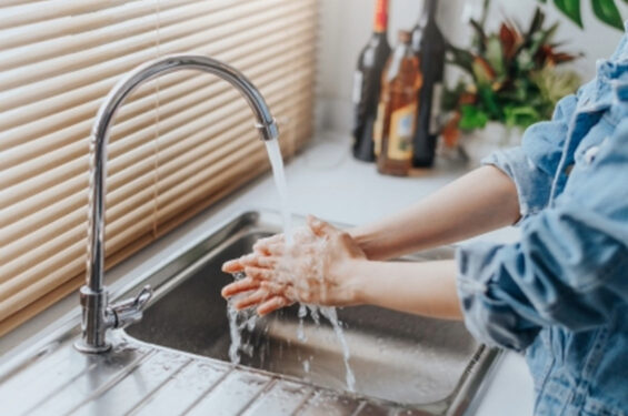 A woman washing her hands in the kitchen sink.