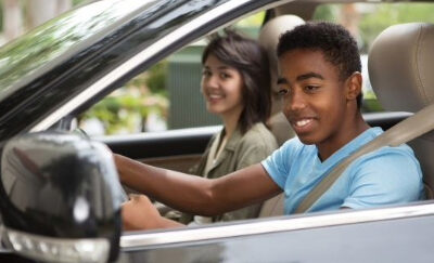 A young driver checking the side mirror while reversing the car.