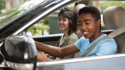 A young driver checking the side mirror while reversing the car.