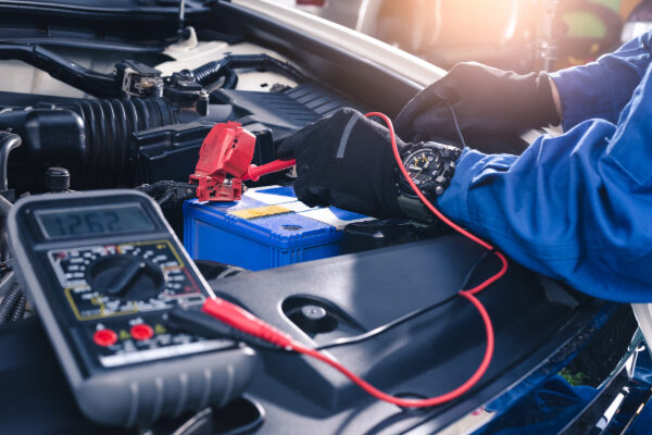 A mechanic wearing gloves as they work on a car battery.