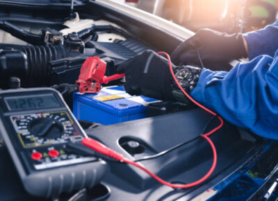 A mechanic wearing gloves as they work on a car battery.