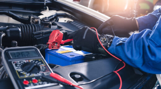 A mechanic wearing gloves as they work on a car battery.