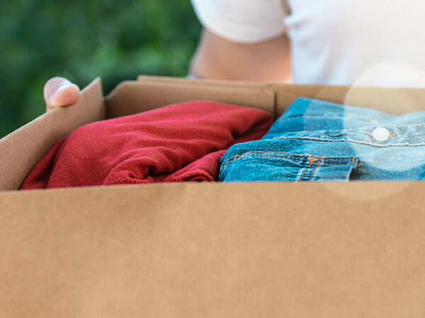 A person holding a cardboard box of clothes.