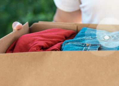 A person holding a cardboard box of clothes.