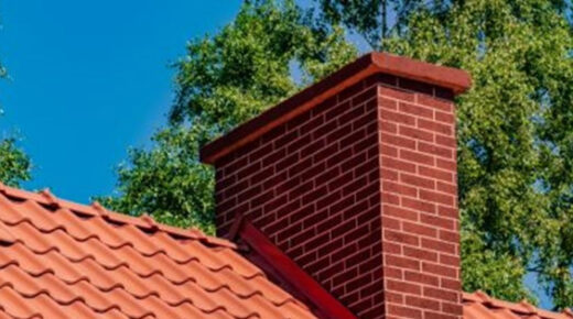 A red brick chimney sitting on top of a terra cotta tile roof.