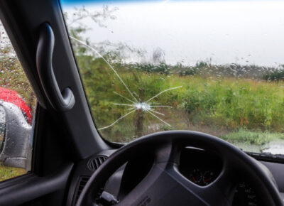 Rain washes over a cracked windshield.