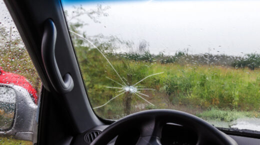 Rain washes over a cracked windshield.