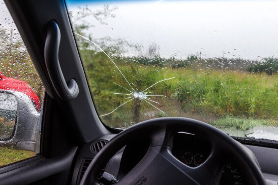 Rain washes over a cracked windshield.
