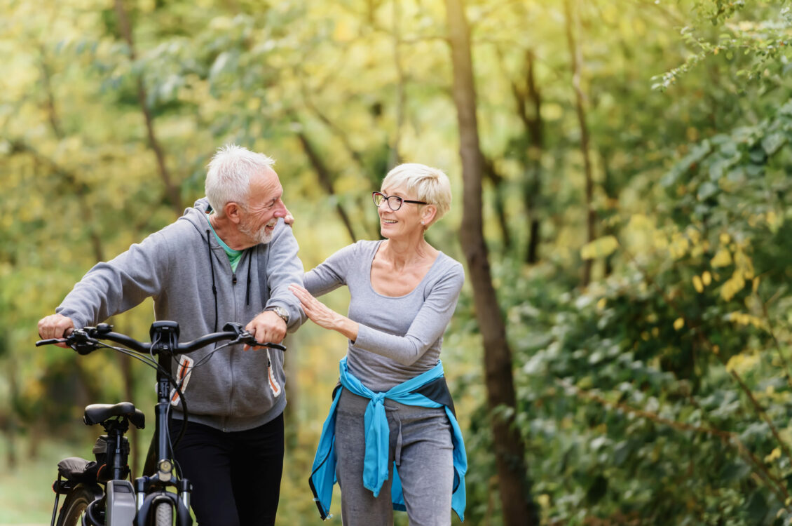 A senior couple outside with a bike.