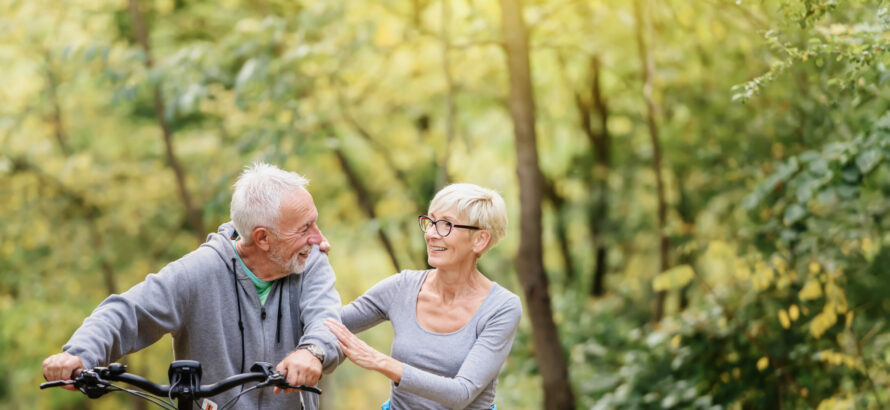 A senior couple outside with a bike.