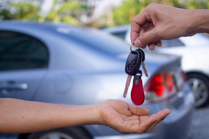 A person handing another person a set of car keys.