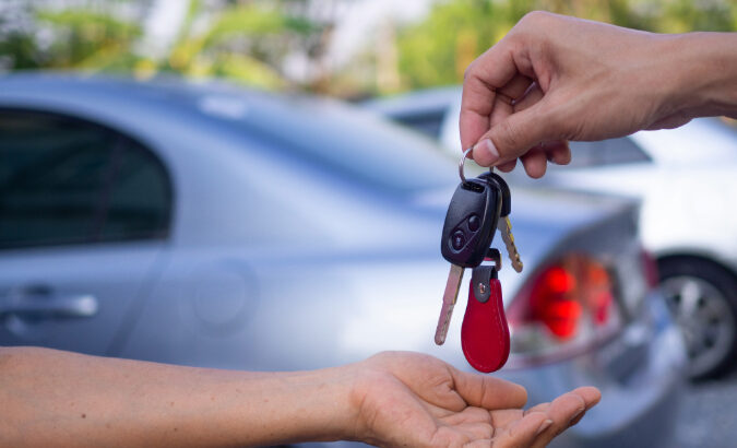 A person handing another person a set of car keys.