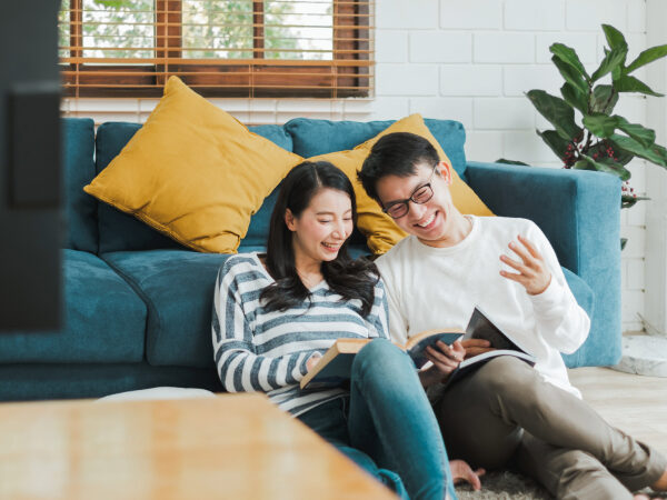 A couple sitting on the floor, looking at books.