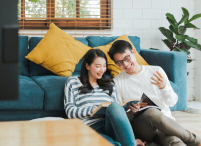 A couple sitting on the floor, looking at books.