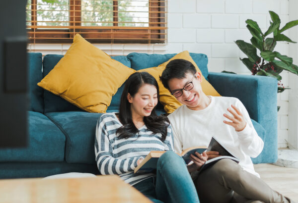 A couple sitting on the floor, looking at books.