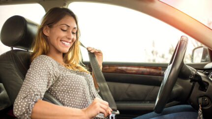 A woman puts on her seatbelt.
