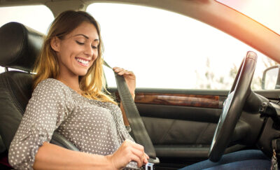 A woman puts on her seatbelt.